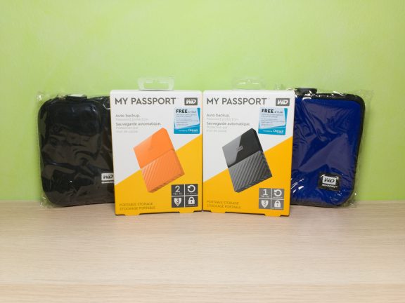 My two new WD My Passport drives, an orange 2 TB drive and a black 1 TB drive; as well as complimentary carrying cases in black and blue.